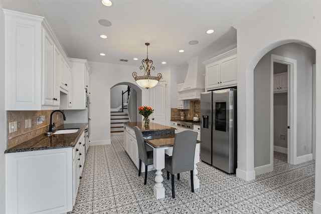 2305 Castle Creek Dr, Mansfield, TX 76063 - kitchen with appliances with stainless steel finishes, arched walkways, premium range hood, white cabinetry, and recessed lighting