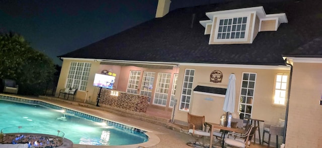 2305 Castle Creek Dr, Mansfield, TX 76063 - pool at night featuring an outdoor pool, a patio area, and french doors