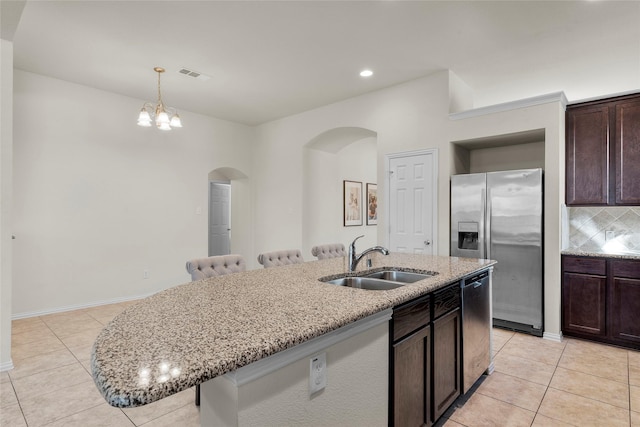 5201 Datewood Ln, Mckinney, TX 75071 - kitchen featuring arched walkways, stainless steel appliances, light tile patterned floors, light stone counters, and dark brown cabinets
