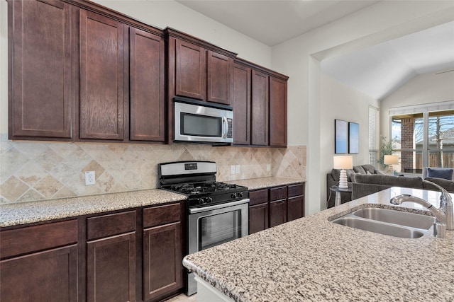 5201 Datewood Ln, Mckinney, TX 75071 - kitchen featuring appliances with stainless steel finishes, open floor plan, backsplash, light stone countertops, and vaulted ceiling