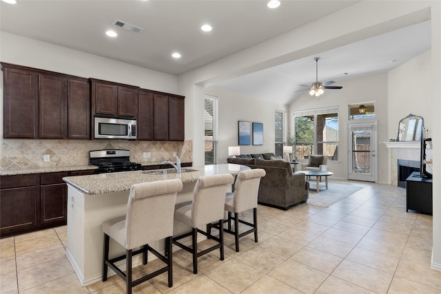 5201 Datewood Ln, Mckinney, TX 75071 - kitchen with stainless steel appliances, decorative backsplash, open floor plan, a breakfast bar area, and light stone countertops