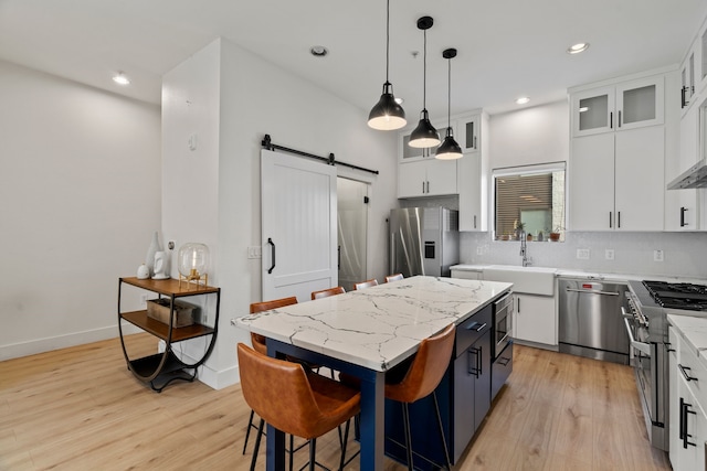 4111 Newton Ave Unit 2, Dallas, TX 75219 - kitchen with appliances with stainless steel finishes, a barn door, light wood finished floors, white cabinets, and recessed lighting