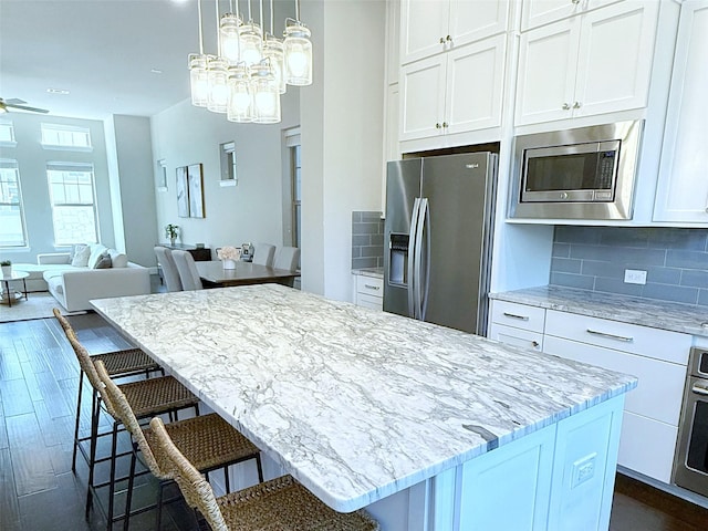 5339 Holland Ave, Dallas, TX 75209 - kitchen featuring stainless steel appliances, a kitchen island, white cabinetry, dark wood finished floors, and open floor plan