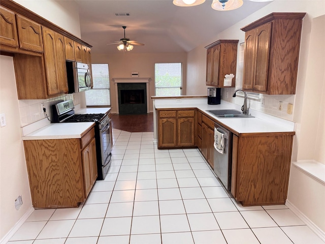 5216 Tartan Cir, Denton, TX 76208 - kitchen with stainless steel appliances, a ceiling fan, decorative backsplash, open floor plan, and a fireplace