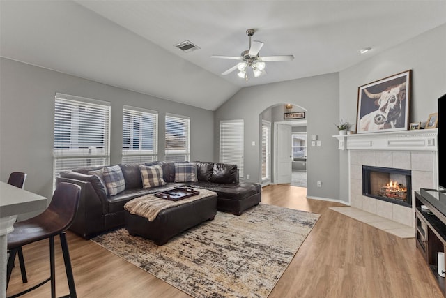 1732 Jasmine Trl, Savannah, TX 76227 - living room featuring arched walkways, ceiling fan, lofted ceiling, light wood-style floors, and a fireplace