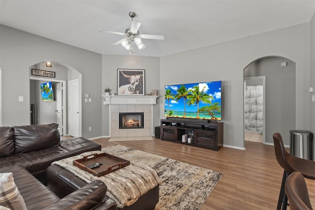 1732 Jasmine Trl, Savannah, TX 76227 - living room featuring arched walkways, ceiling fan, wood finished floors, and a tile fireplace
