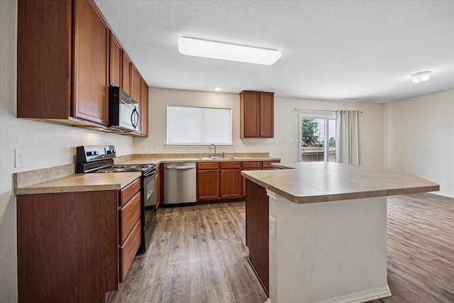 330 Broken Bow, Krum, TX 76249 - kitchen featuring black appliances, light wood finished floors, a center island, brown cabinets, and light countertops