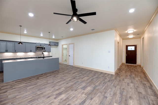 2621 Canton Dr, Fort Worth, TX 76112 - kitchen with stainless steel microwave, a kitchen island with sink, light wood finished floors, light countertops, and ceiling fan