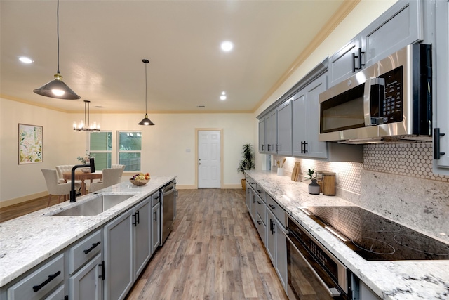 2621 Canton Dr, Fort Worth, TX 76112 - kitchen with stainless steel appliances, gray cabinetry, light wood-style flooring, tasteful backsplash, and ornamental molding