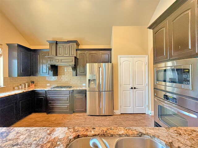 14249 Fall Harvest Dr, Frisco, TX 75033 - kitchen with stainless steel appliances, decorative backsplash, light stone countertops, light wood finished floors, and lofted ceiling