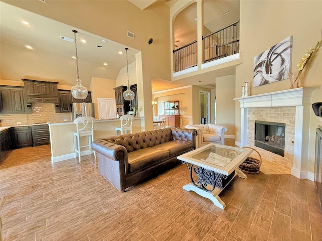 14249 Fall Harvest Dr, Frisco, TX 75033 - living room featuring light wood-type flooring, a towering ceiling, a brick fireplace, and recessed lighting
