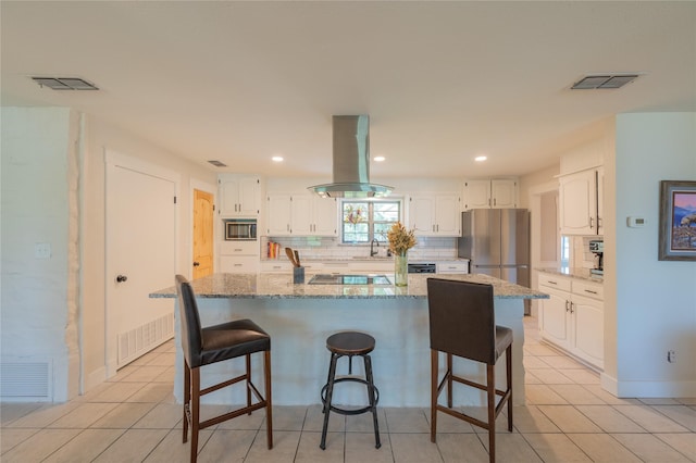 18 Tula Ct, Nocona, TX 76255 - kitchen with island range hood, stainless steel appliances, white cabinets, light stone countertops, and tasteful backsplash
