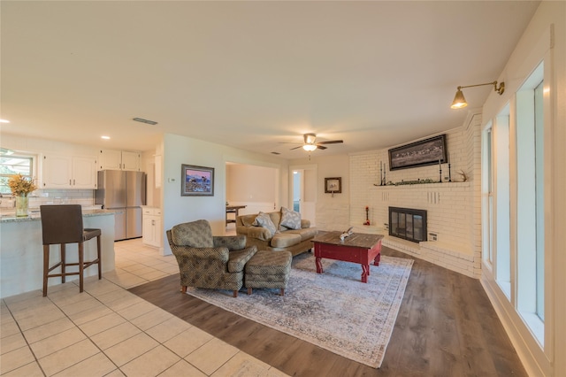 18 Tula Ct, Nocona, TX 76255 - living area featuring a brick fireplace, ceiling fan, and light wood-style flooring