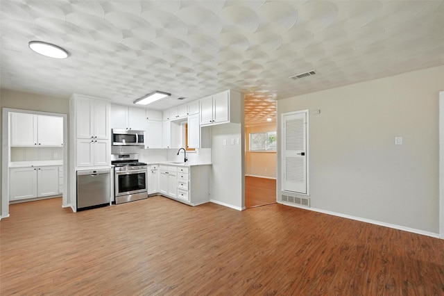 324 Jasmine Ct, Burleson, TX 76028 - kitchen with appliances with stainless steel finishes, light countertops, light wood-style flooring, and white cabinetry