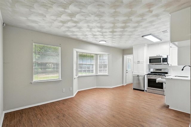 324 Jasmine Ct, Burleson, TX 76028 - kitchen with stainless steel appliances, light wood-style floors, light countertops, white cabinetry, and backsplash