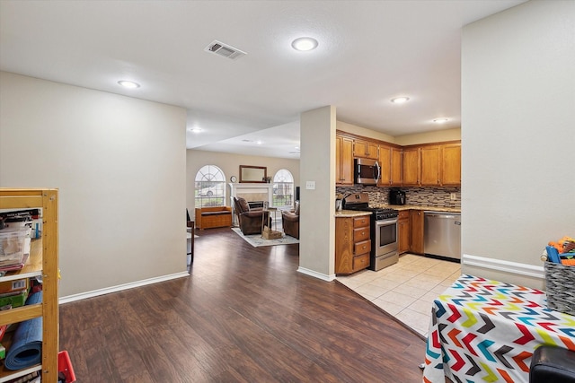 1112 Indian Ridge Dr, Denton, TX 76205 - kitchen with appliances with stainless steel finishes, light wood finished floors, backsplash, open floor plan, and brown cabinets