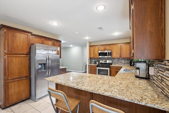 1112 Indian Ridge Dr, Denton, TX 76205 - kitchen with appliances with stainless steel finishes, a peninsula, backsplash, light stone countertops, and recessed lighting