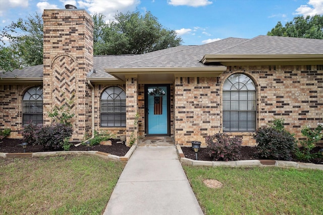 1112 Indian Ridge Dr, Denton, TX 76205 - property entrance with a shingled roof, brick siding, a chimney, and a yard