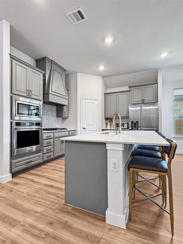 3978 Sidney Ln, Heath, TX 75126 - kitchen with stainless steel appliances, gray cabinets, custom range hood, decorative backsplash, and light countertops