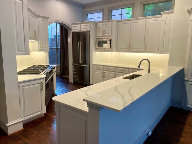 4139 Herschel Ave, Dallas, TX 75219 - kitchen with premium appliances, dark wood-type flooring, light stone countertops, a peninsula, and decorative backsplash