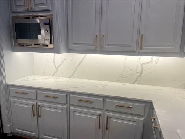 4139 Herschel Ave, Dallas, TX 75219 - kitchen featuring stainless steel microwave, tasteful backsplash, light stone countertops, and gray cabinetry