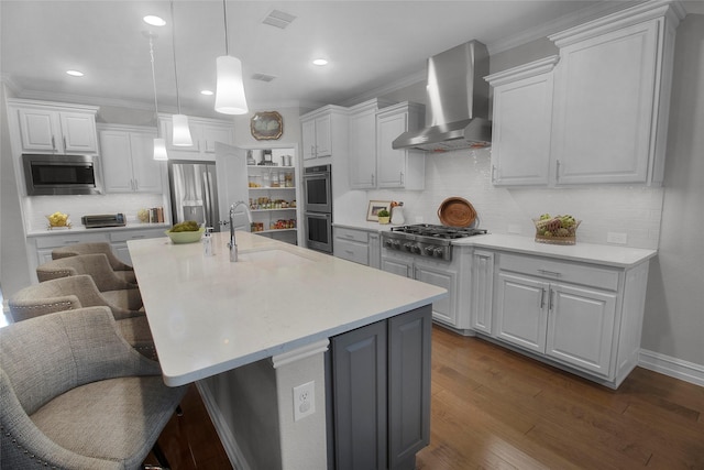 717 Freedom Ln, Aubrey, TX 76227 - kitchen featuring stainless steel appliances, wall chimney exhaust hood, tasteful backsplash, white cabinets, and a kitchen breakfast bar