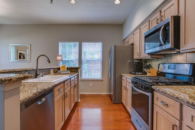 18423 Rain Dance Trl, Dallas, TX 75252 - kitchen featuring appliances with stainless steel finishes, decorative backsplash, light wood-style flooring, light stone countertops, and recessed lighting