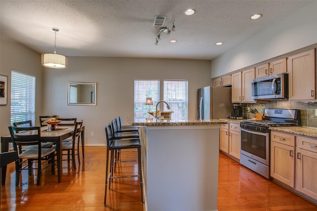 18423 Rain Dance Trl, Dallas, TX 75252 - kitchen featuring appliances with stainless steel finishes, a textured ceiling, light wood-style flooring, decorative backsplash, and light stone countertops