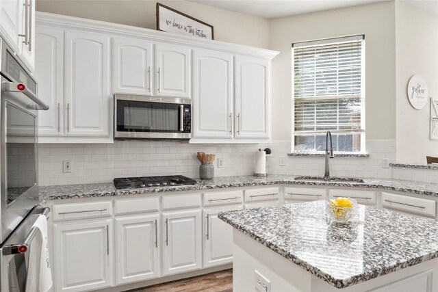 204 Oregon Trl, Argyle, TX 76226 - kitchen with stainless steel appliances, tasteful backsplash, white cabinets, and light stone counters