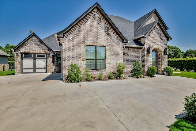 1001 Quarry Ct, Granbury, TX 76048 - french provincial home featuring brick siding, a garage, driveway, and roof with shingles
