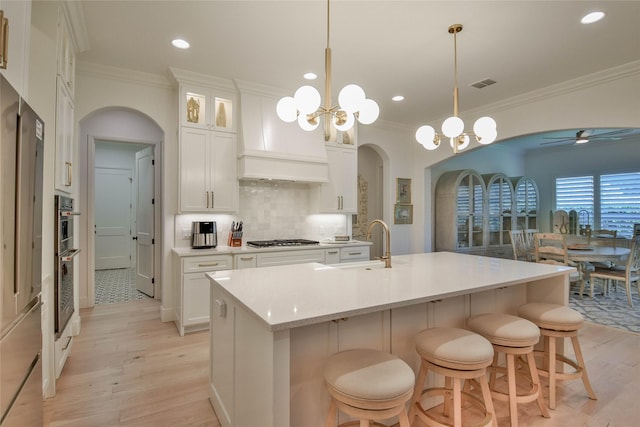 1001 Quarry Ct, Granbury, TX 76048 - kitchen with arched walkways, ornamental molding, light wood finished floors, appliances with stainless steel finishes, and ceiling fan
