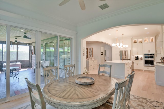 1001 Quarry Ct, Granbury, TX 76048 - dining space featuring a ceiling fan, arched walkways, light wood finished floors, crown molding, and recessed lighting