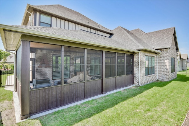1001 Quarry Ct, Granbury, TX 76048 - back of property featuring a sunroom, brick siding, board and batten siding, roof with shingles, and a lawn