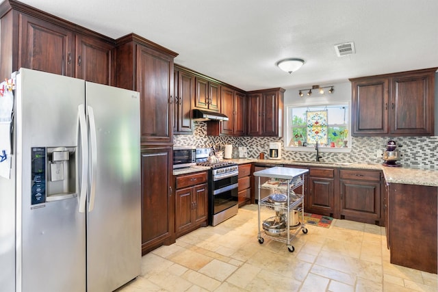 845 Griffith Ave, Terrell, TX 75160 - kitchen featuring stainless steel appliances, tasteful backsplash, under cabinet range hood, light stone countertops, and dark brown cabinets
