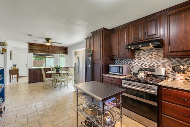 845 Griffith Ave, Terrell, TX 75160 - kitchen featuring stainless steel appliances, under cabinet range hood, ceiling fan, tasteful backsplash, and stone tile floors