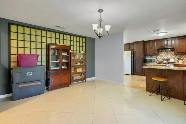 845 Griffith Ave, Terrell, TX 75160 - kitchen with appliances with stainless steel finishes, a chandelier, under cabinet range hood, tasteful backsplash, and light stone counters