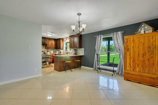 845 Griffith Ave, Terrell, TX 75160 - kitchen featuring decorative backsplash, a peninsula, a chandelier, hanging light fixtures, and light tile patterned floors