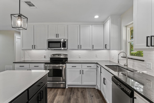 1007 Monte Carlo Dr, Grand Saline, TX 75140 - kitchen with stainless steel appliances, dark stone counters, white cabinets, decorative light fixtures, and recessed lighting