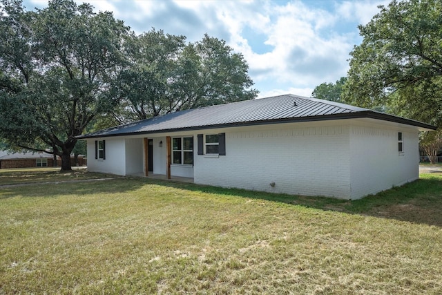 1007 Monte Carlo Dr, Grand Saline, TX 75140 - back of property with brick siding, a lawn, and a metal roof