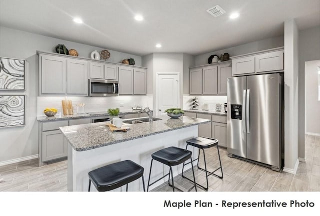 1806 Iris, Melissa, TX 75454 - kitchen featuring appliances with stainless steel finishes, a breakfast bar, gray cabinetry, wood tiled floors, and recessed lighting