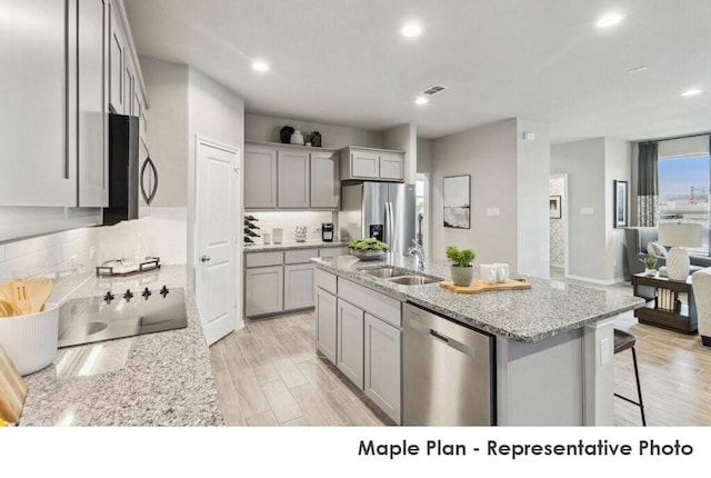 1806 Iris, Melissa, TX 75454 - kitchen featuring appliances with stainless steel finishes, gray cabinets, tasteful backsplash, a center island with sink, and light stone countertops