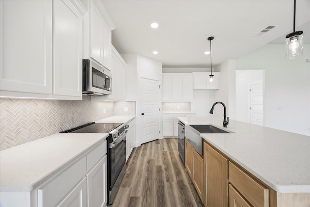 5150 Fox Trot Ln, Caddo Mills, TX 75135 - kitchen with appliances with stainless steel finishes, wood finished floors, backsplash, a center island with sink, and hanging light fixtures