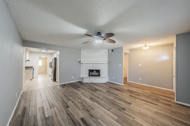 5105 French Wood Dr, Arlington, TX 76016 - unfurnished living room featuring ceiling fan, wood finished floors, a fireplace, and a textured ceiling