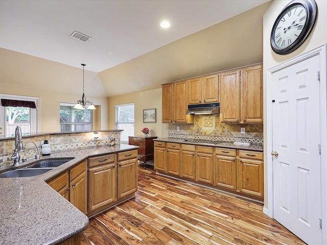 1597 Sweetbriar Dr, Allen, TX 75002 - kitchen with under cabinet range hood, light wood-type flooring, cooktop, backsplash, and vaulted ceiling