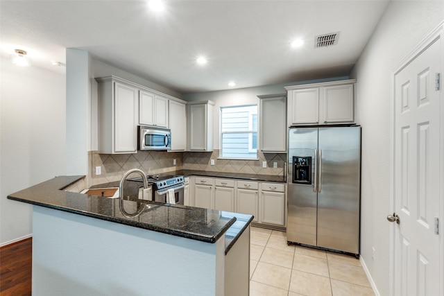 7416 Coronado Ave Unit 14, Dallas, TX 75214 - kitchen with appliances with stainless steel finishes, dark stone countertops, tasteful backsplash, a peninsula, and recessed lighting
