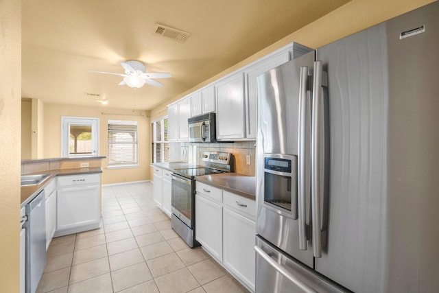 108 Bear Trl, Waxahachie, TX 75165 - kitchen featuring appliances with stainless steel finishes, backsplash, ceiling fan, light tile patterned floors, and white cabinetry