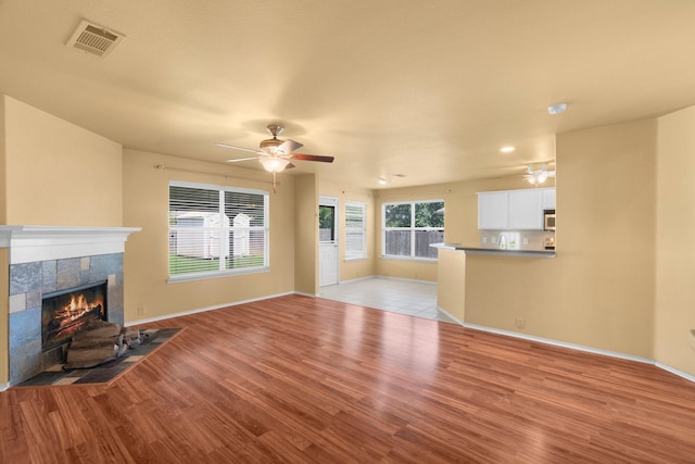 108 Bear Trl, Waxahachie, TX 75165 - unfurnished living room with ceiling fan, a tiled fireplace, light wood-style floors, and recessed lighting