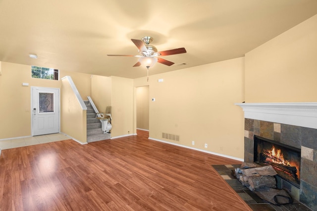 108 Bear Trl, Waxahachie, TX 75165 - unfurnished living room featuring stairway, a tile fireplace, ceiling fan, and wood finished floors
