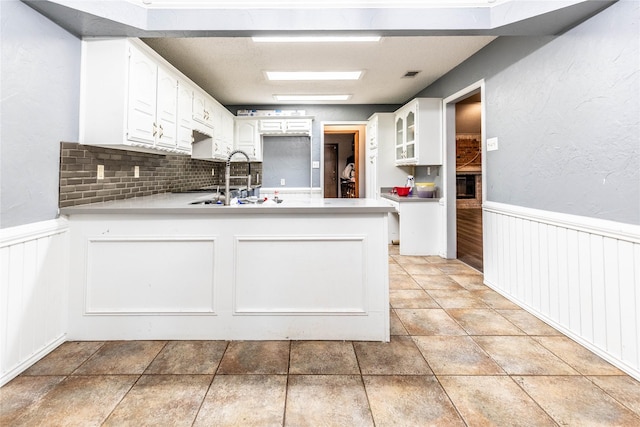 1237 Linkwood Ln, Lancaster, TX 75146 - kitchen with a peninsula, white cabinets, a wainscoted wall, light countertops, and backsplash