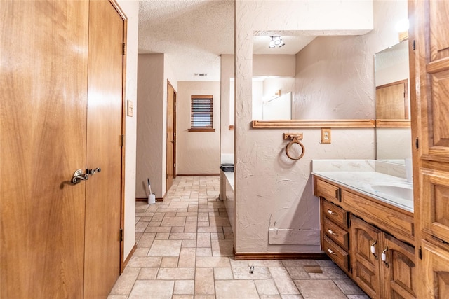 1237 Linkwood Ln, Lancaster, TX 75146 - bathroom featuring stone tile flooring, vanity, a textured ceiling, and a textured wall